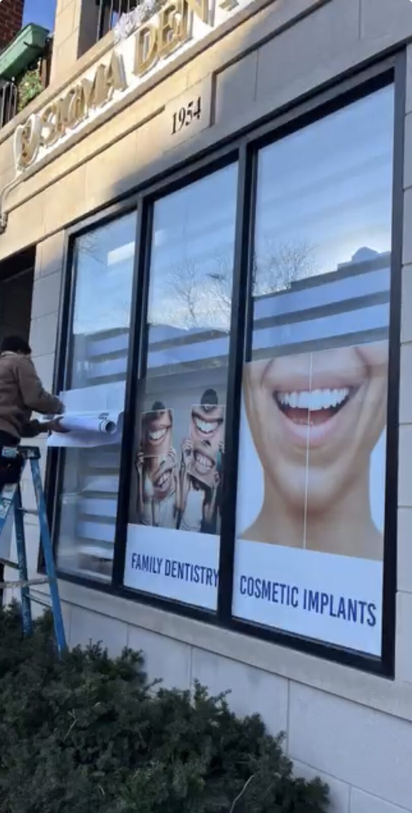 Printed window graphics of smiling patients on a dental office storefront