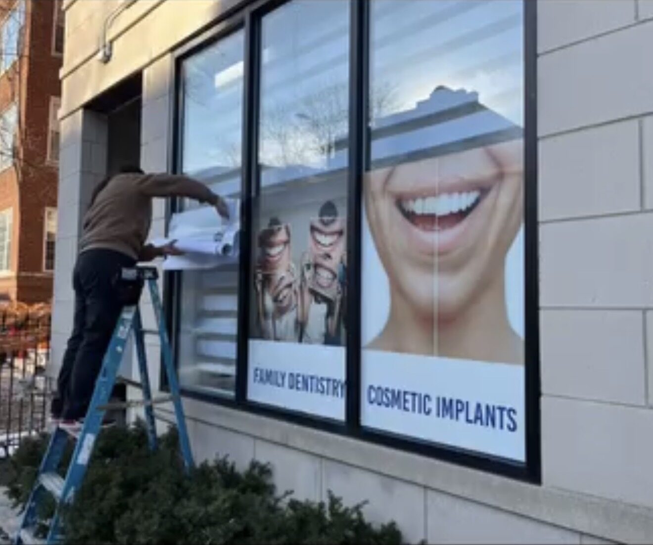 Installer applying printed window perf to office glass