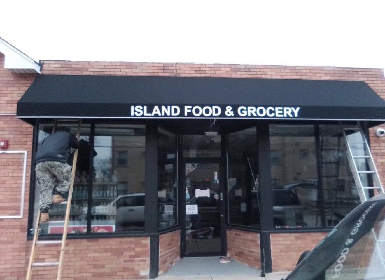 Installer on a ladder mounting awning lettering