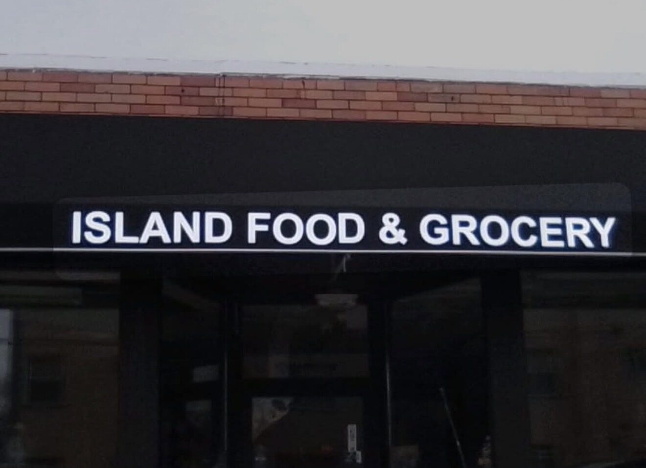 Island Food and Grocery awning lettering illuminated after dark