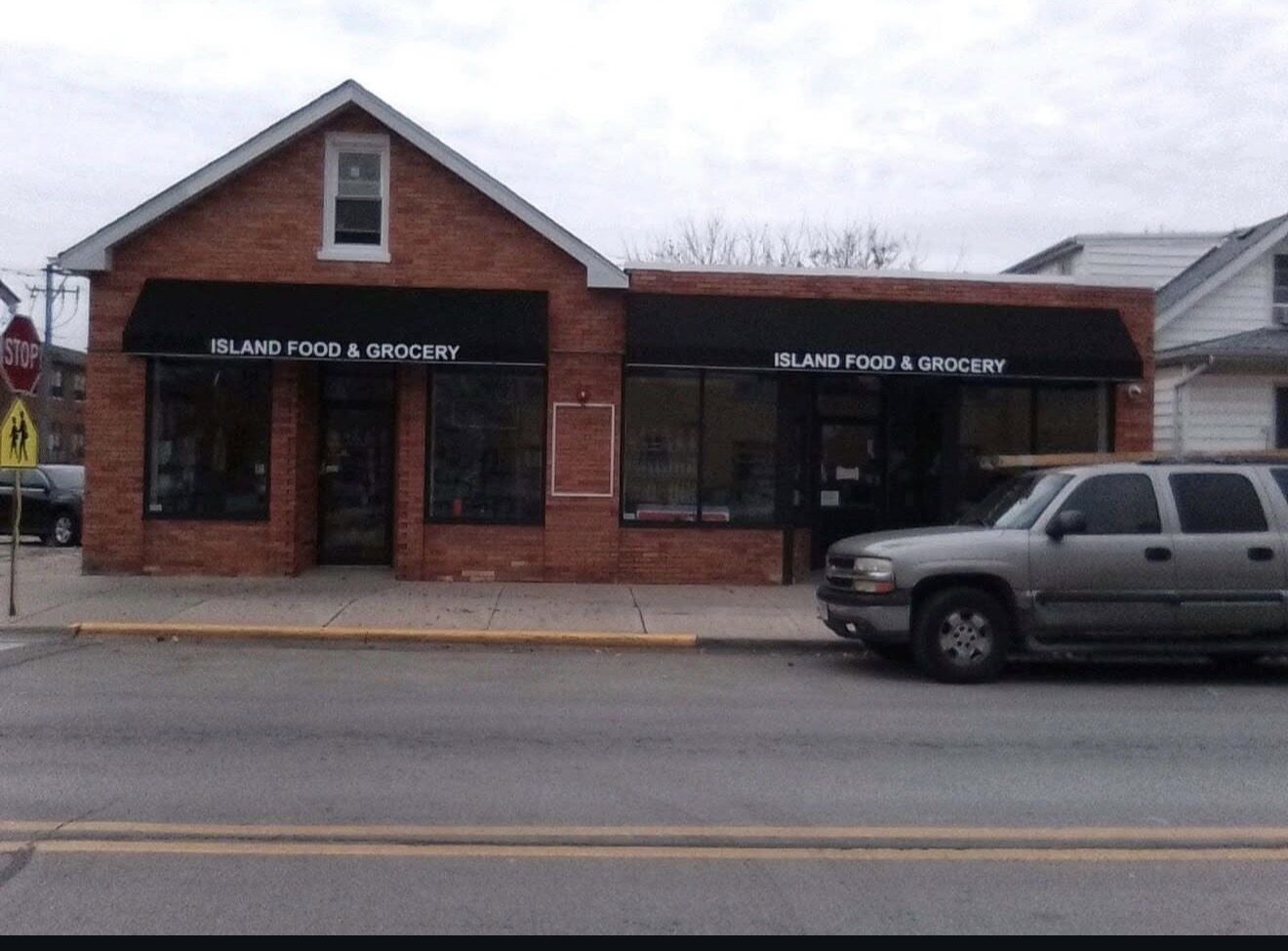 Island Food and Grocery storefront with two black awnings lettered in white