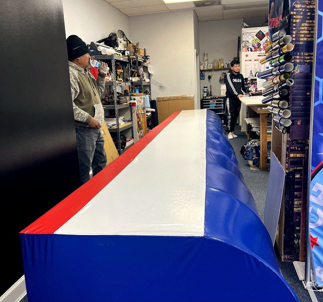 Crew member working a long red, white and blue banner down the shop table