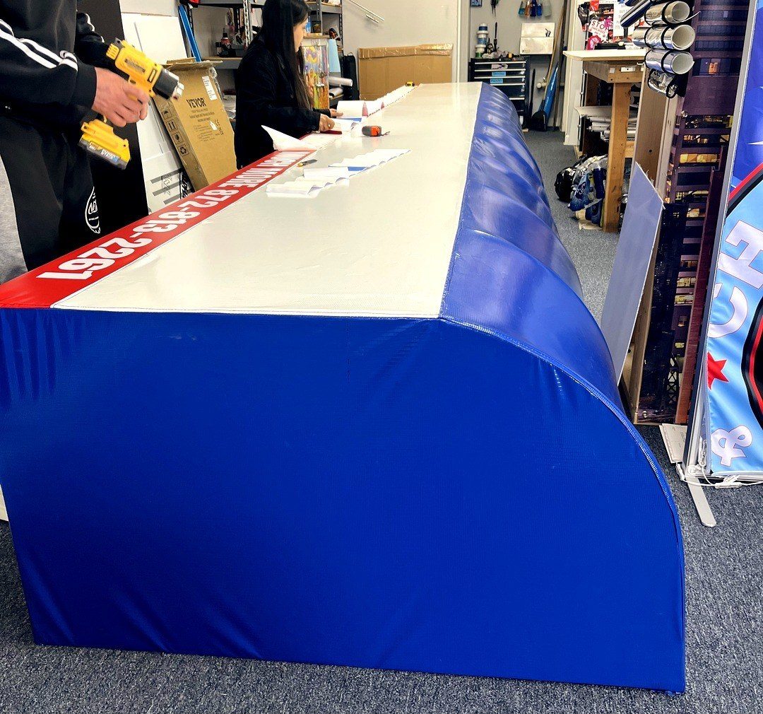 Blue and red banner material laid out on the shop work table during finishing