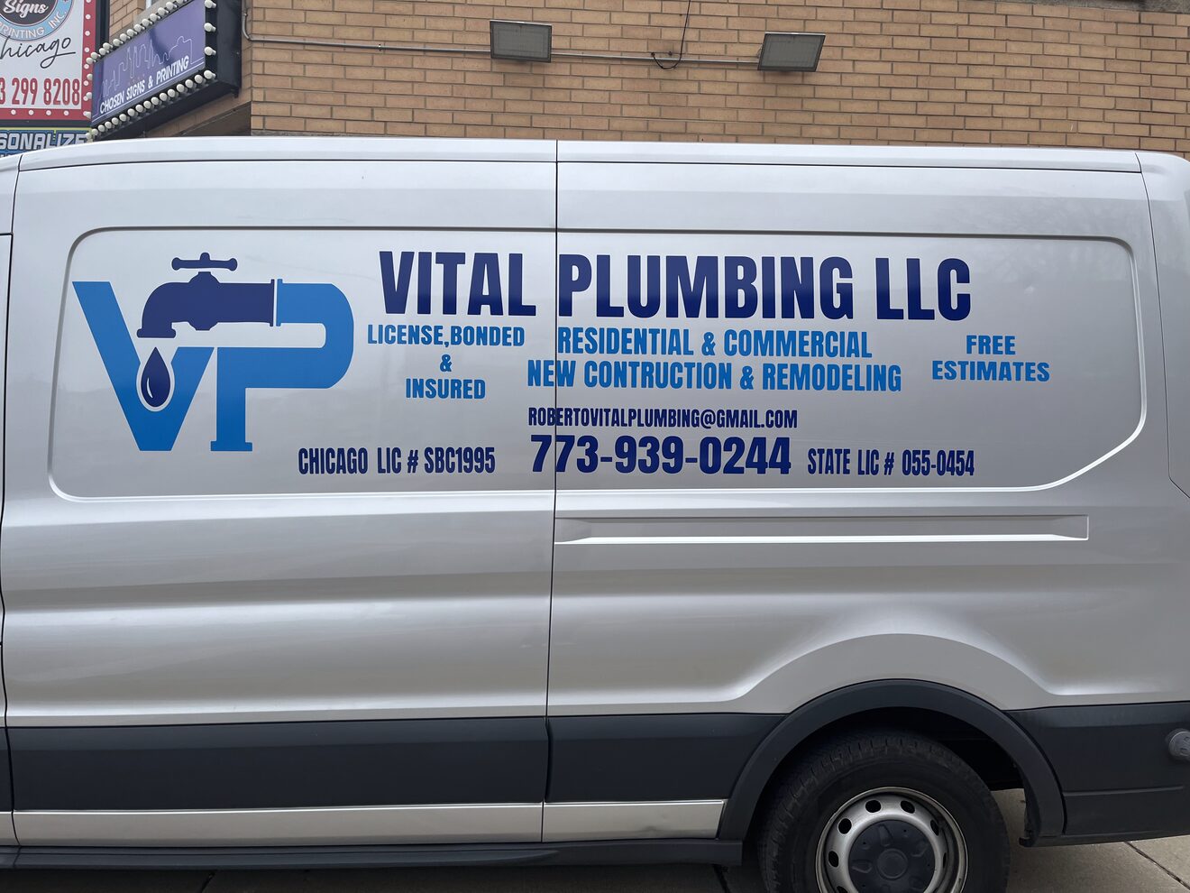 White cargo van lettered with the Vital Plumbing logo, services and phone number